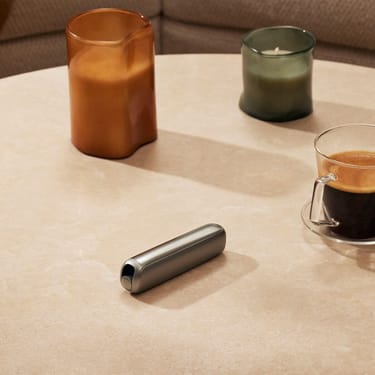 Ploom AURA front panel Lunar Silver accessory on a table.